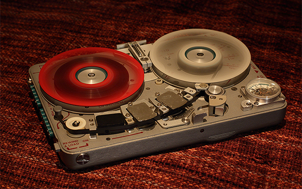Foto di un registratore spia con una bobina di nastro rossa e una grigia.