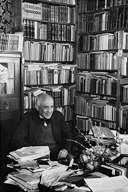 Ein freundlich lächelnder Jonas Fränkel am Schreibtisch in seiner Bibliothek im Jahr 1948, fotografiert von Margit Schildhauser.