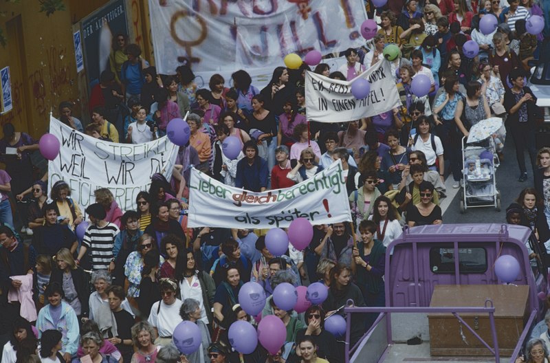 Demonstrationszug streikender Frauen mit Transparenten und lila Ballonen