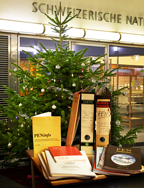 Das Bild zeigt Bundesordner, Broschüren und Protokolle des Deutschschweizer PEN Zentrums sowie des PEN International. Diese Archvalien gehören zum Bestand des Schweizerischen Literaturarchivs SLA. Als Bildhintergrund wurde aus aktuellem Anlass der Weihnachtsbaum beim Eingang in die NB gewählt.