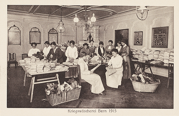 Women sorting laundry for the troops on tables in a windowless room.