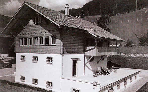 Full view of a chalet that has atypical features for the Bernese Oberland region: little wood and high walls.