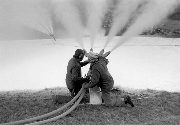 Deux « faiseurs de neige » apprennent à utiliser un canon à neige de type Larchmont le jour de la mise en service de la première grande installation d’enneigement d’Europe à Savognin. Celui de gauche est Not Spinatsch, celui de droite un inconnu.